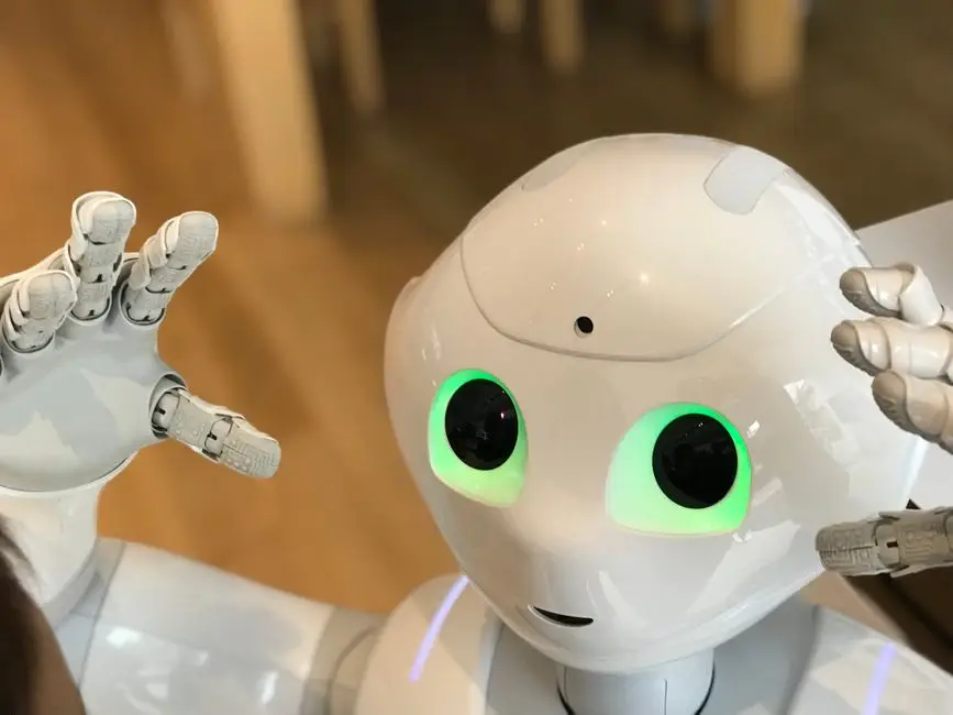 Robot siedzący przy biurku z dokumentami i laptopem, symbolizujący nowoczesną technologię w służbie tłumaczeń